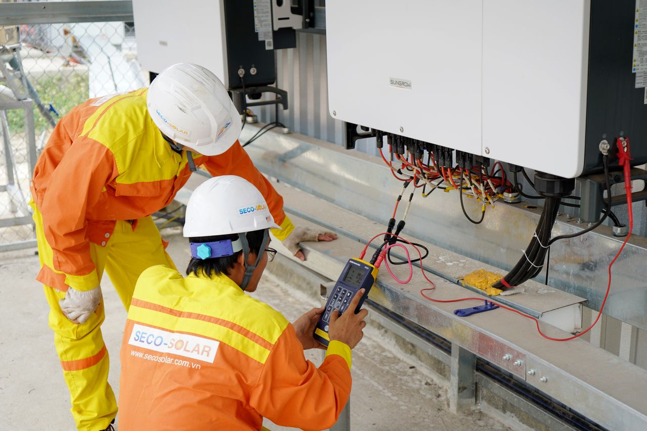 services-img Two electrical engineers installing and testing solar power systems wearing safety gear at a construction site.